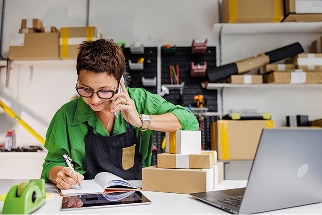 Woman on the phone writing something in a notebook