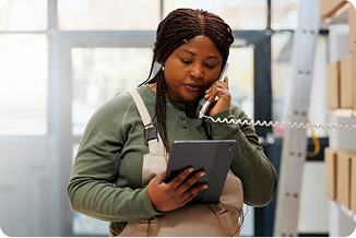 Woman on the phone looking down at a tablet that she's holding in her hand