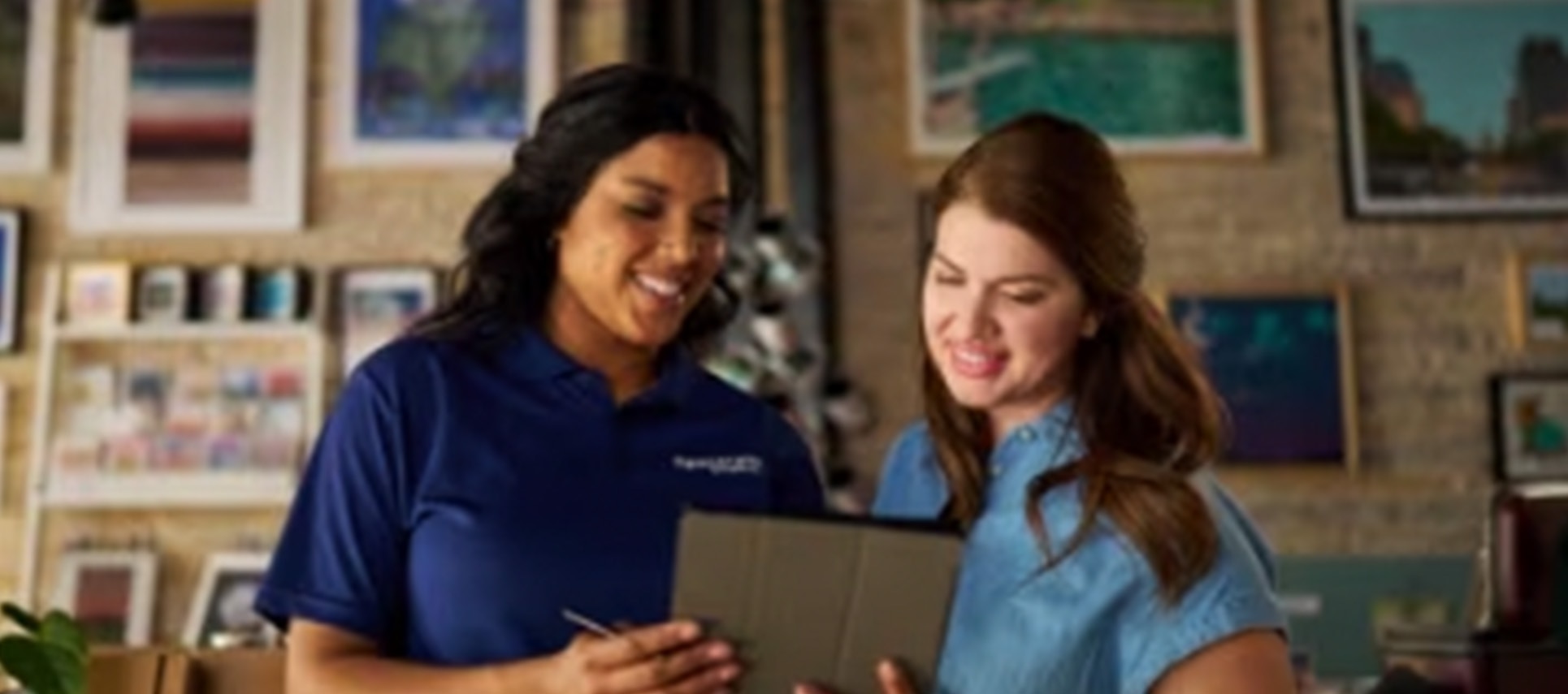 Two women smiling with tablet in art studio