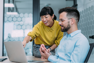 Woman helping man with something on laptop