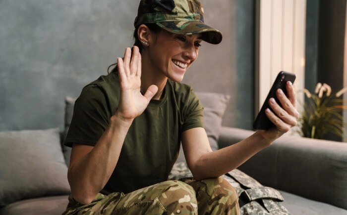 Military woman waving hello while video-chatting on her cell phone using Spectrum Mobile.