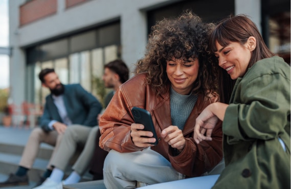Dos mujeres usando un dispositivo móvil al aire libre