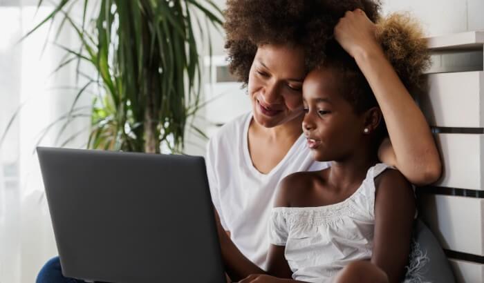 A mother and daughter sitting down, using Spectrum Internet on a laptop.