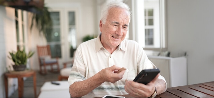 Elderly man using Spectrum Mobile's hearing aid-compatible handsets and screen reader-compatible applications