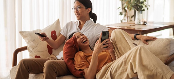 A couple using devices on a couch