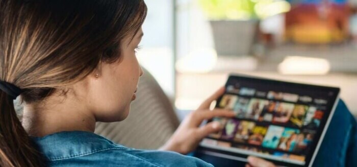 A young woman streaming content on her tablet with Spectrum