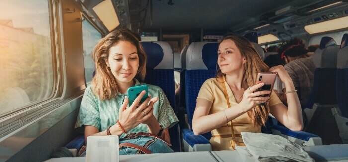 Two women on a train using Spectrum Mobile's international coverage