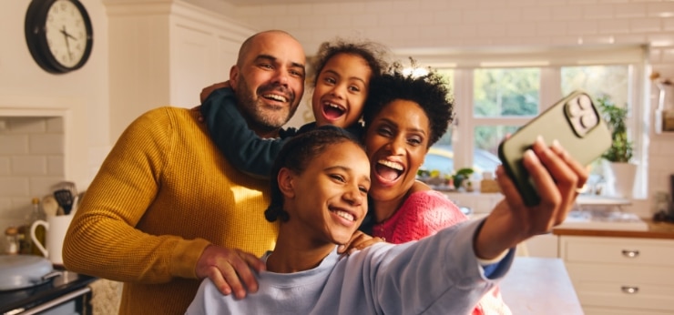 Mother, father and two daughters taking a selfie with a Spectrum Mobile cell phone.