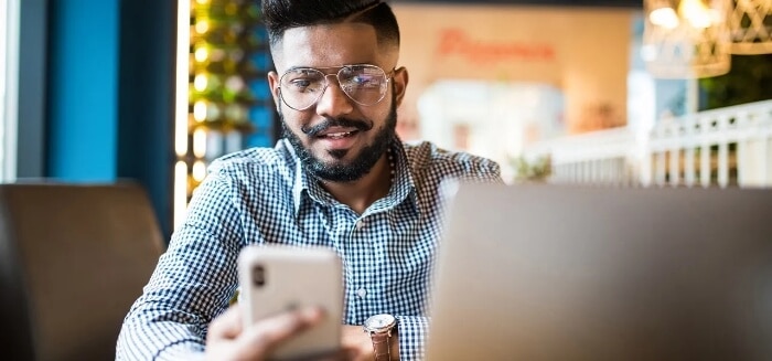 A man interacting with a mobile phone and laptop