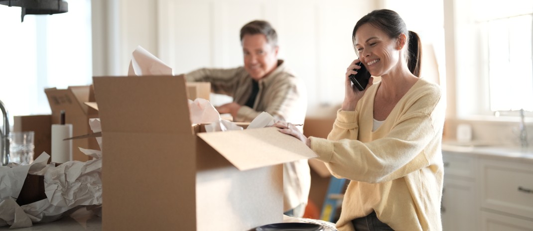 Una pareja está de pie junto a un escritorio, mirando una tableta mientras comprueban la disponibilidad del servicio de Internet en casa.