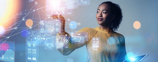 Business woman holding tablet uses her other hand to interact with futuristic, hologram charts in front of her.