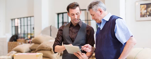 Two businessmen have a conversation while looking at a notepad