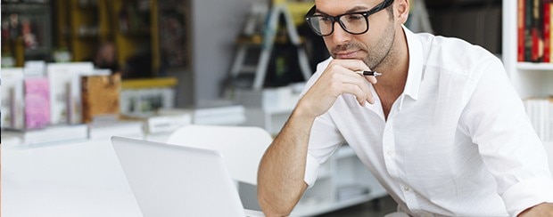 Businessman looking at laptop with his hand on his chin 