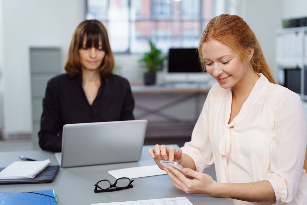 Two women and a man gathered around a laptop.