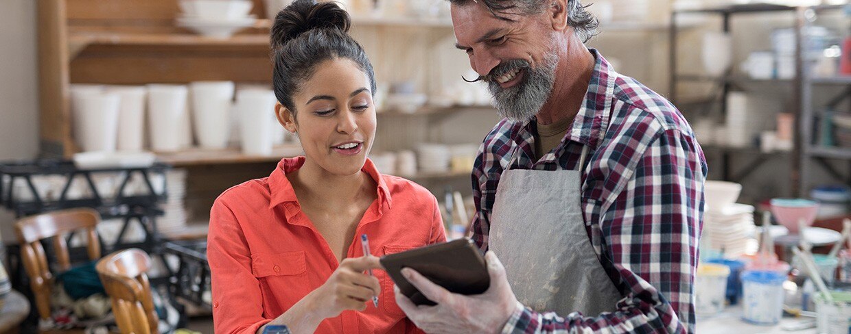 Male and female potter discussing over tablet