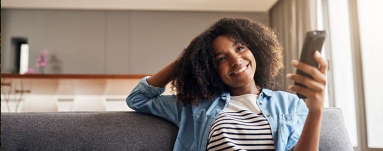 Smiling woman holding a TV remote.