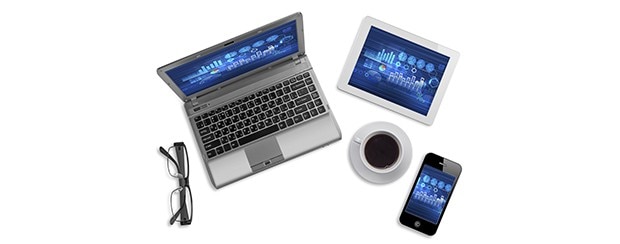 Laptop, tablet, smartphone, cup of coffee, and eyeglasses arranged on a white surface