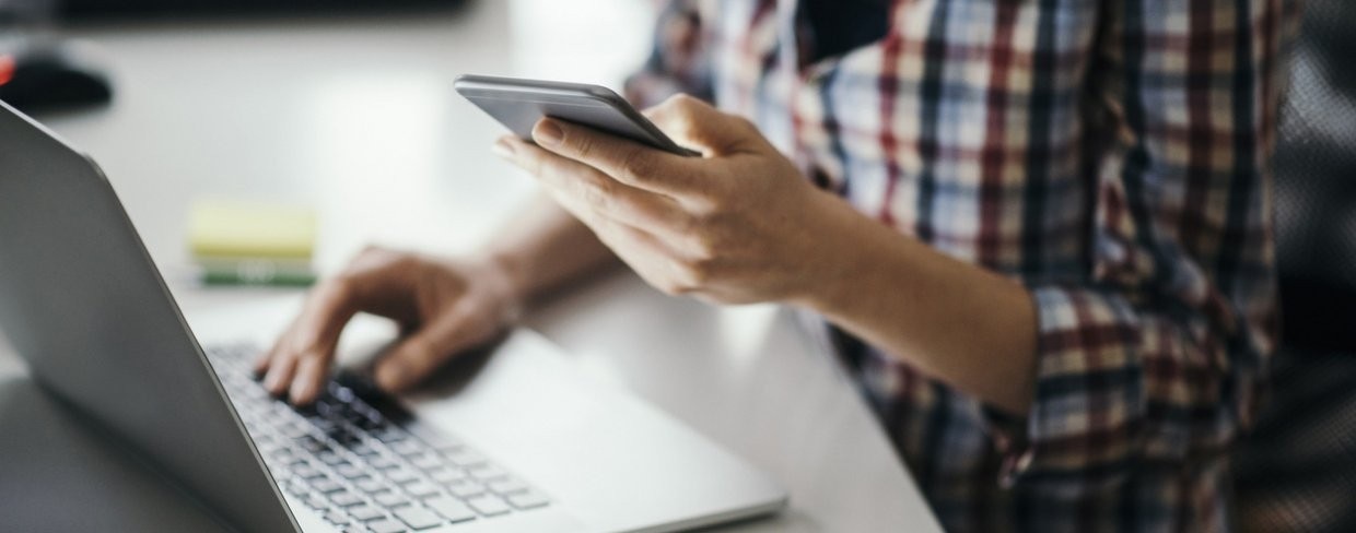 Business person uses laptop and smart phone