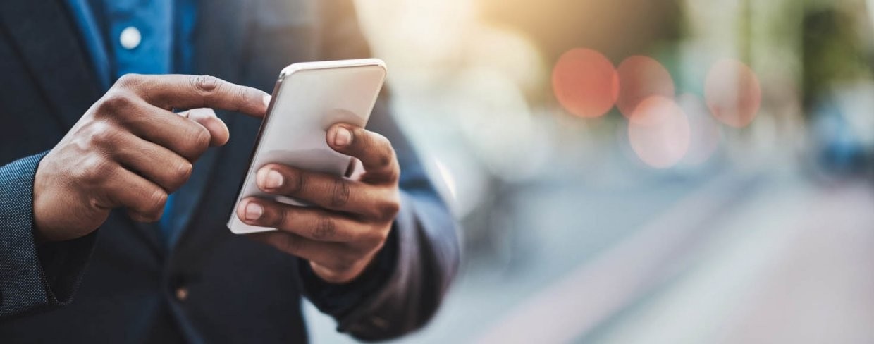 Business man standing on the street using a smartphone to text.