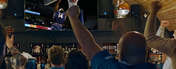 Fans cheering while watching a basketball game at a bar