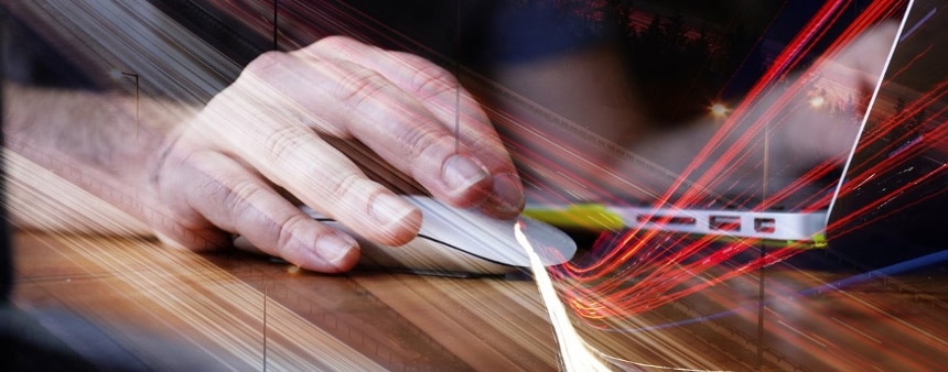 Man’s hand uses mouse connected to laptop with images of internet fiber superimposed over it.