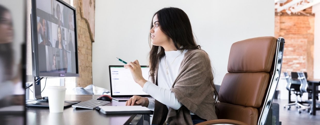 Woman in business meeting via video call at office desk with laptop 