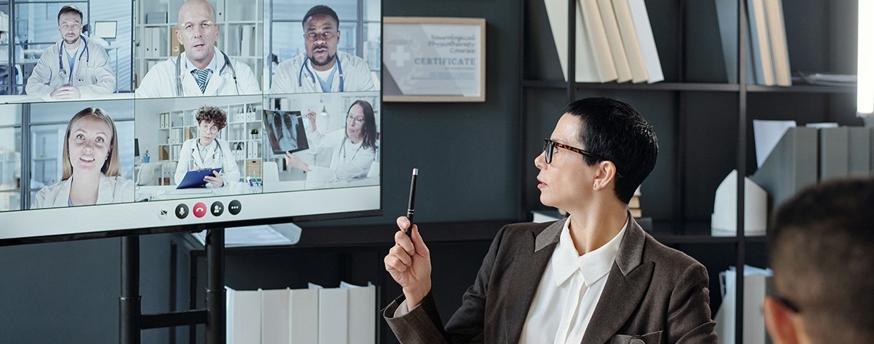 Female leader pointing at video chat screen with pen