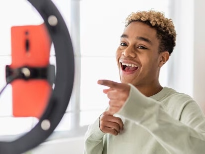 Young man pointing at a phone on a light ring.