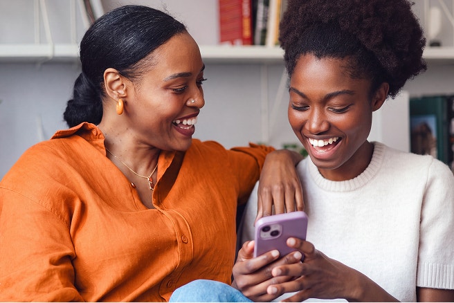 Mother and daughter using mobile device indoors