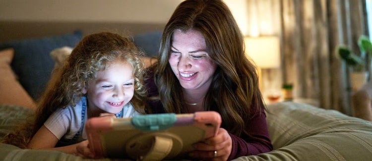 Una mujer y una niña sonrientes compartiendo una tableta.