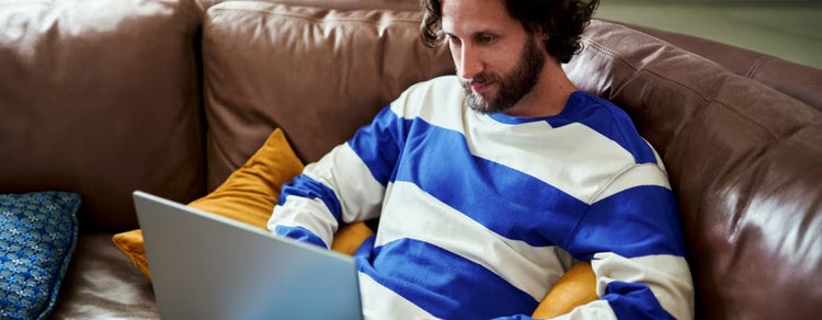 Hombre sentado en un sillón y mirando una laptop