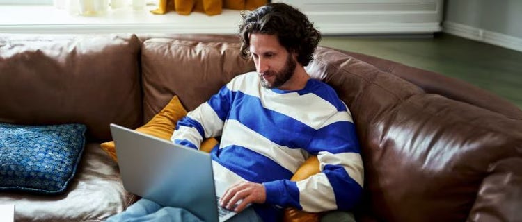 Persona escribiendo en una laptop sosteniendo un teléfono celular, superposición del ícono de un candado, botón de inicio de sesión, campos de nombre de usuario y contraseña.