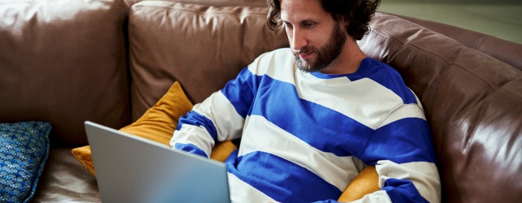 Man sitting on couch and looking at laptop