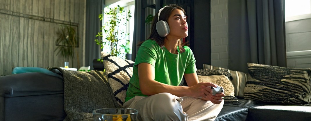 A hand pressing a button on a TV remote in front of a TV.