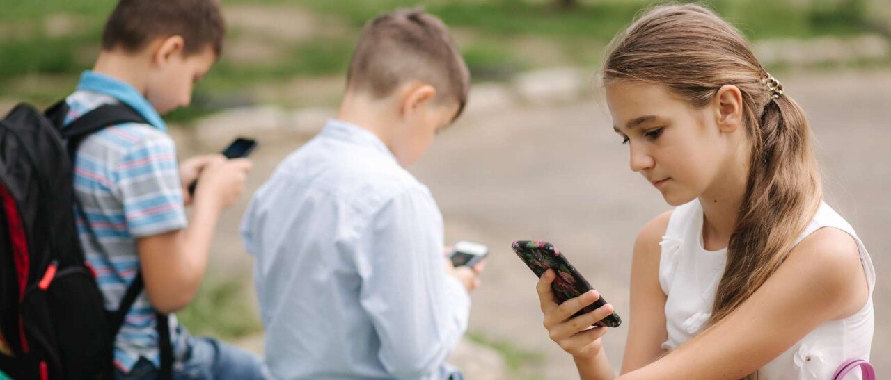 Two boys and a girl using cell phones.