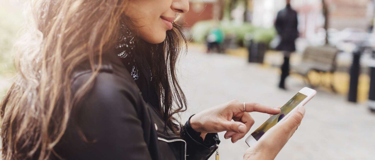Female Spectrum Mobile customer pointing at her cell phone screen.