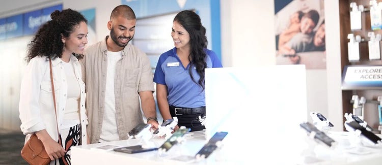 Customers reviewing smartphones with store associate at Spectrum store