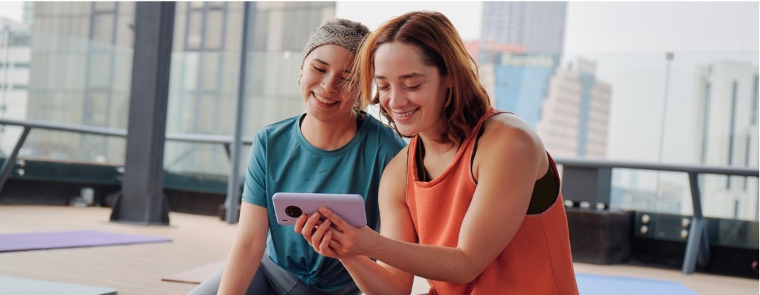 Dos mujeres sonriendo mirando un teléfono.