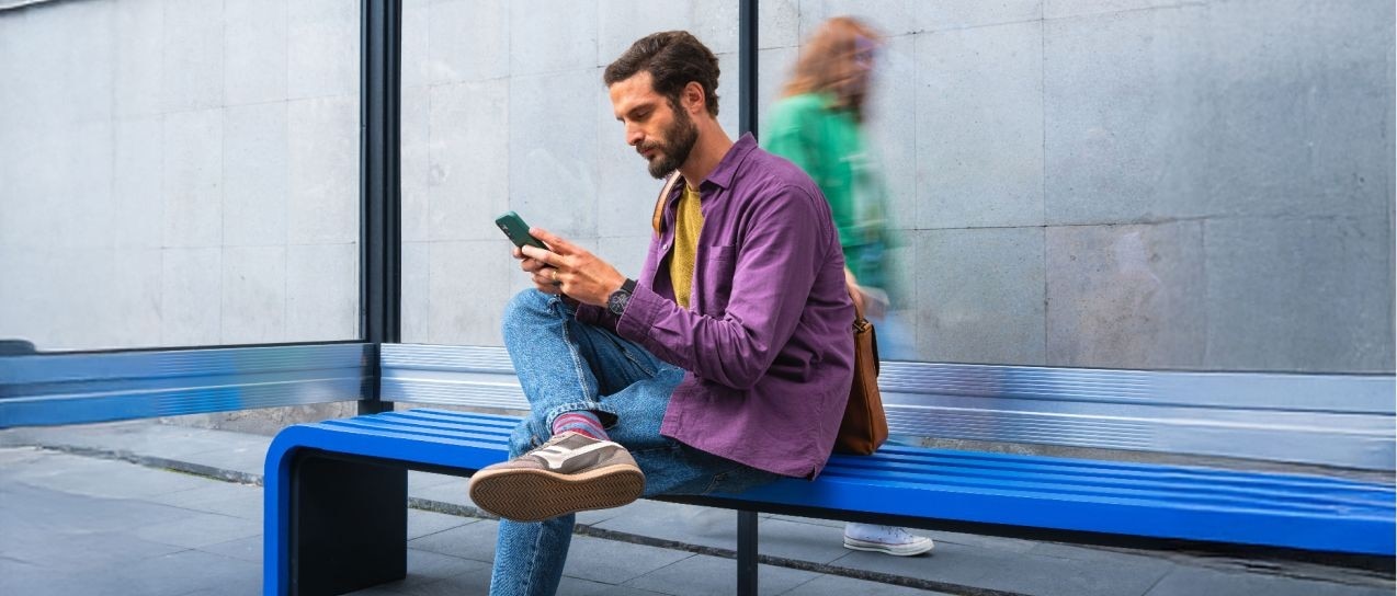 Hombre mirando su teléfono, sonriendo.