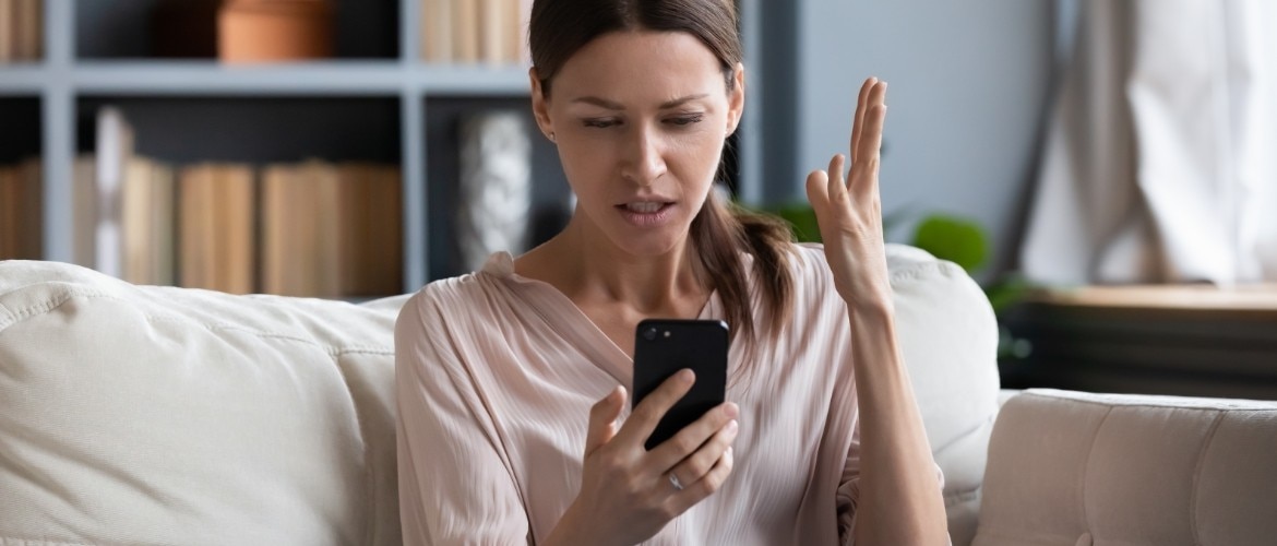 Una mujer mirando su teléfono, frustrada por haber recibido llamadas no deseadas