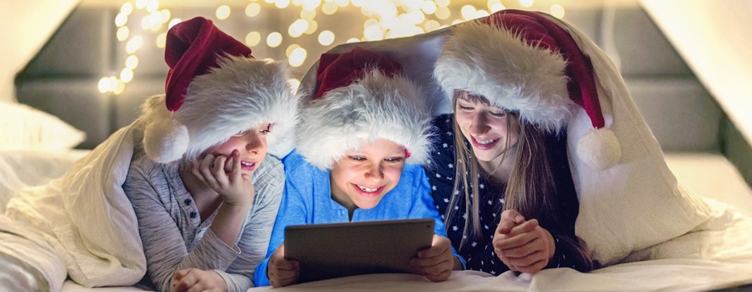 A hand pressing a button on a TV remote in front of a TV.