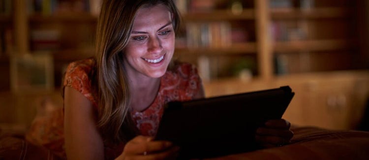 A woman using a tablet while smiling.