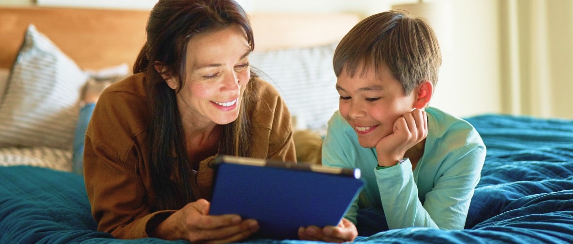 A hand pressing a button on a TV remote in front of a TV.
