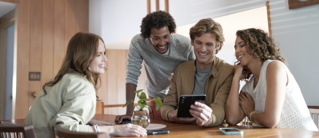 A man and boy sitting on a couch together, looking at a tablet. 
