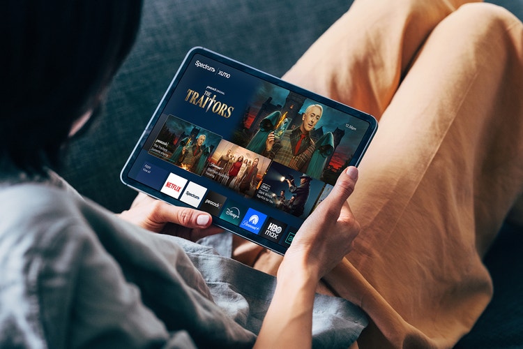 Woman sitting down using the Xumo app on a tablet.
