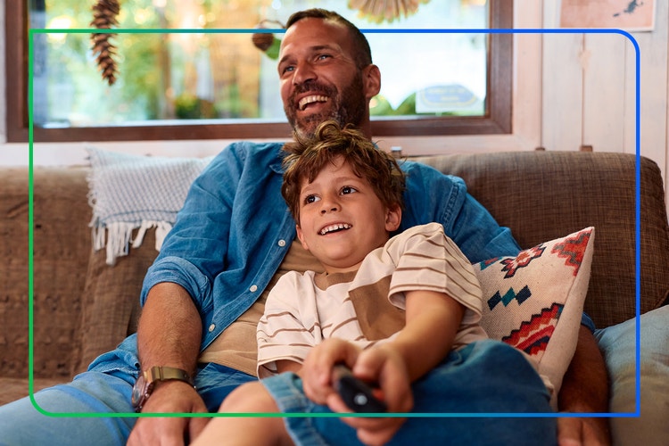 Father and son watching tv together on a couch