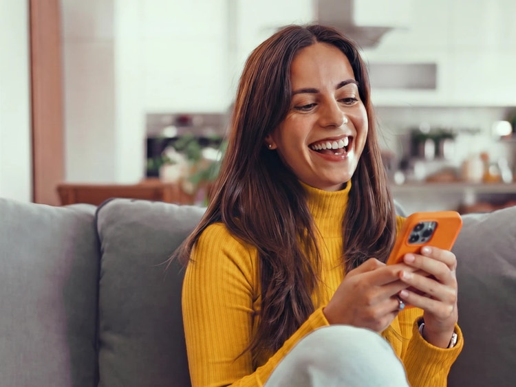 Smiling woman sitting on couch using mobile device